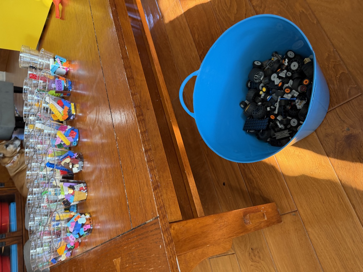 Rows of cups filled with colorful Lego pieces set out for open-ended building