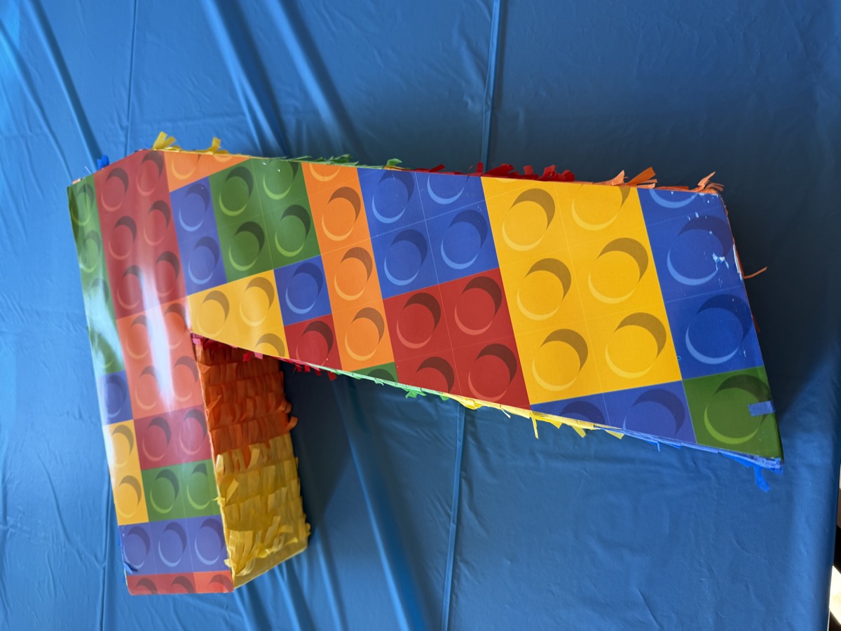 A Lego-brick "7" piñata covered in colorful brick patterns, ready for the big smash