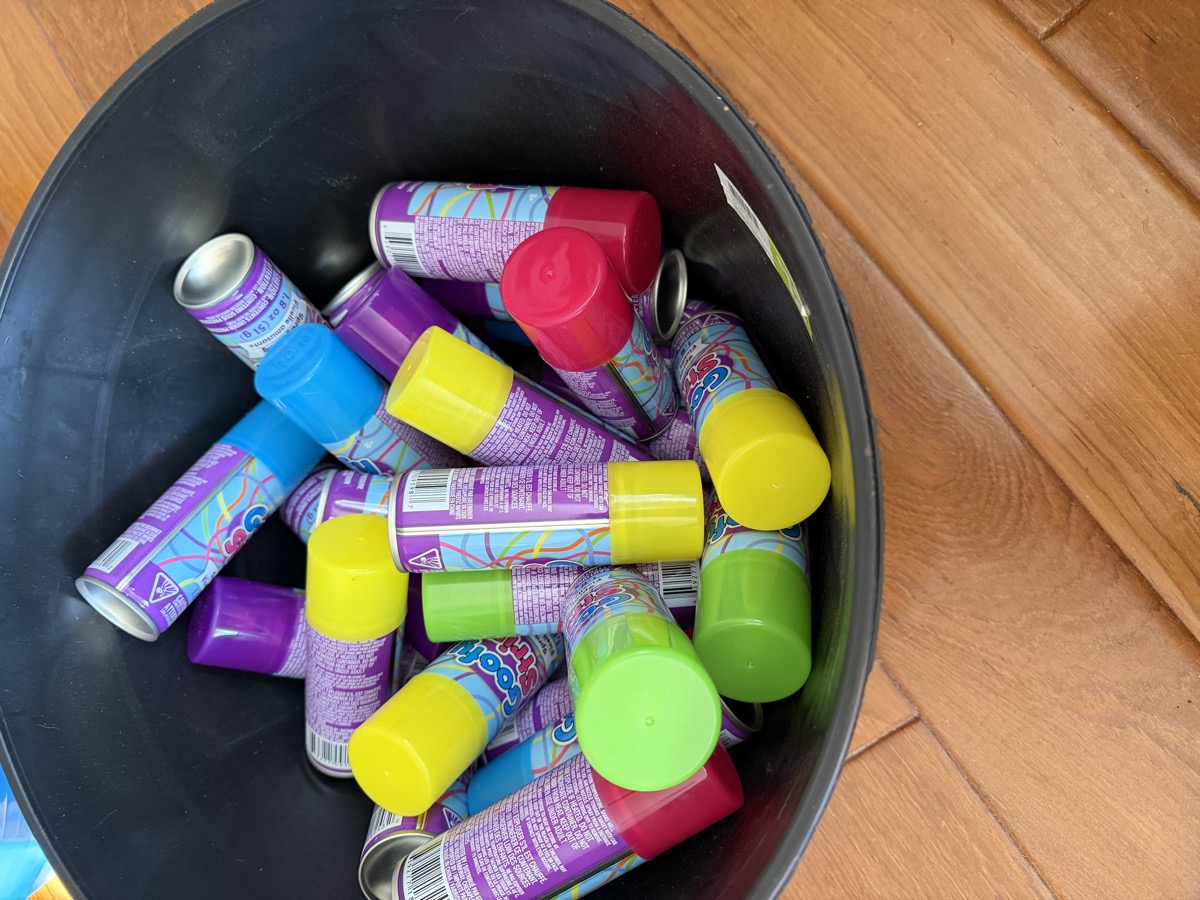 A bucket of colorful cans of silly string, ready for the water and string battle