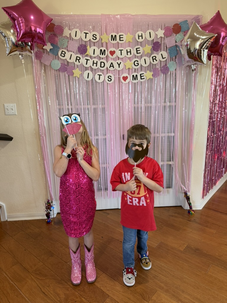 Photo-op backdrop with birthday girl and guest posing with funny face props